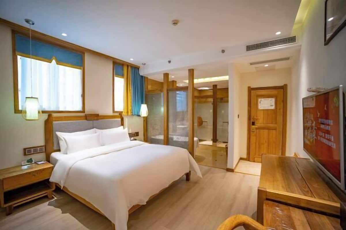 A hotel room with a large bed, wooden headboard, bedside tables, a desk, and a television.