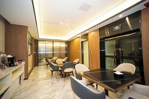 A hotel room with a dining area, a minibar, and a view of the elevator.
