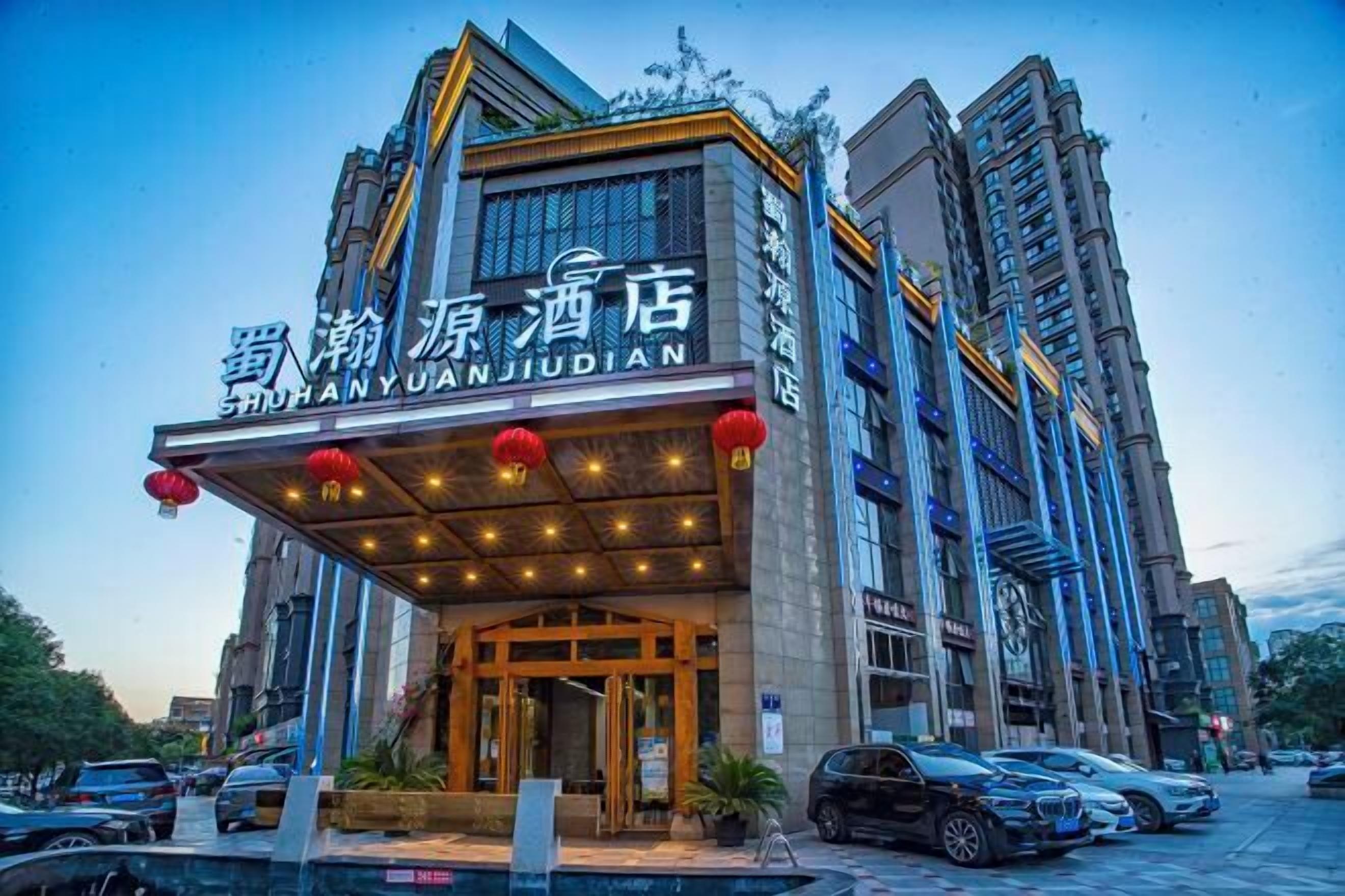 A hotel with a modern facade, large windows, and a prominent entrance with red lanterns.