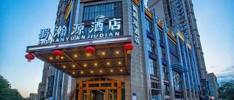 A hotel with a modern facade, large windows, and a prominent entrance with red lanterns.