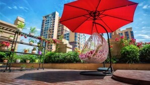 A red umbrella, a hanging chair, and a wooden deck with potted plants. - Shuhanyuan Hotel Mianyang (Mianyang)