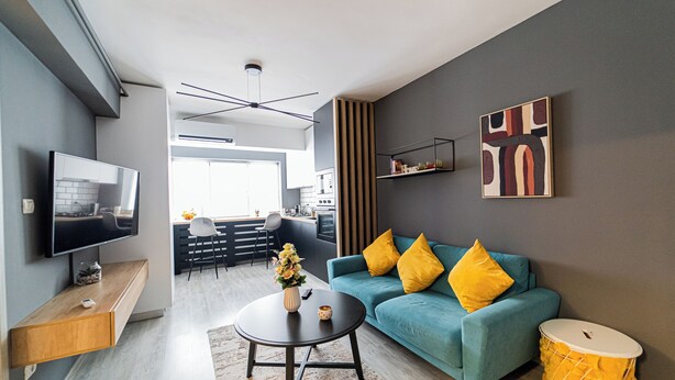 Ein modernes Wohnzimmer mit einem türkisfarbenen Sofa, einem Flachbildfernseher, einem Couchtisch und einer Trommel.