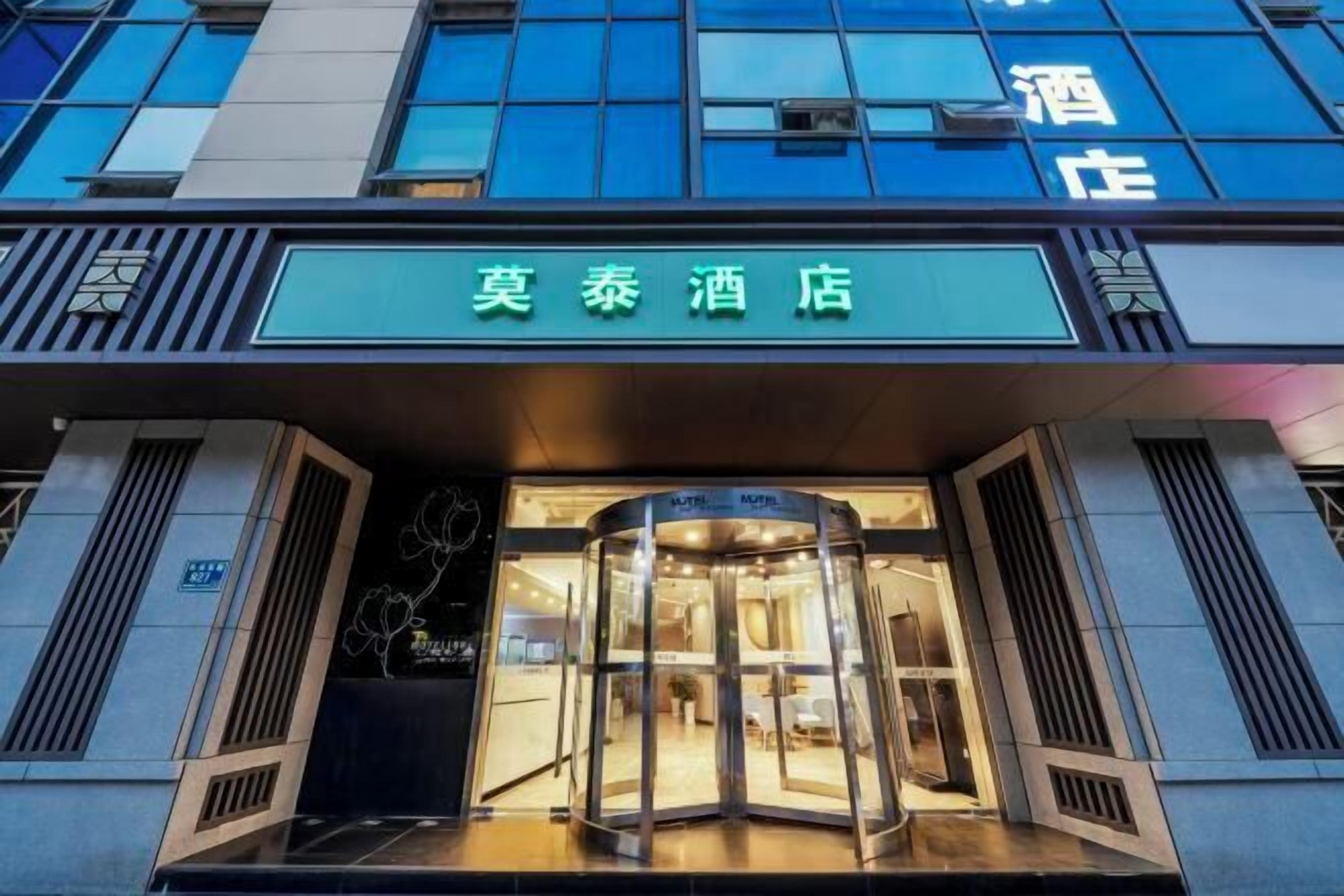 The entrance of a hotel with a revolving door and a sign above it.