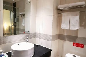 Un baño con un lavabo redondo, un espejo, una cabina de ducha de vidrio y un perchero para toallas.