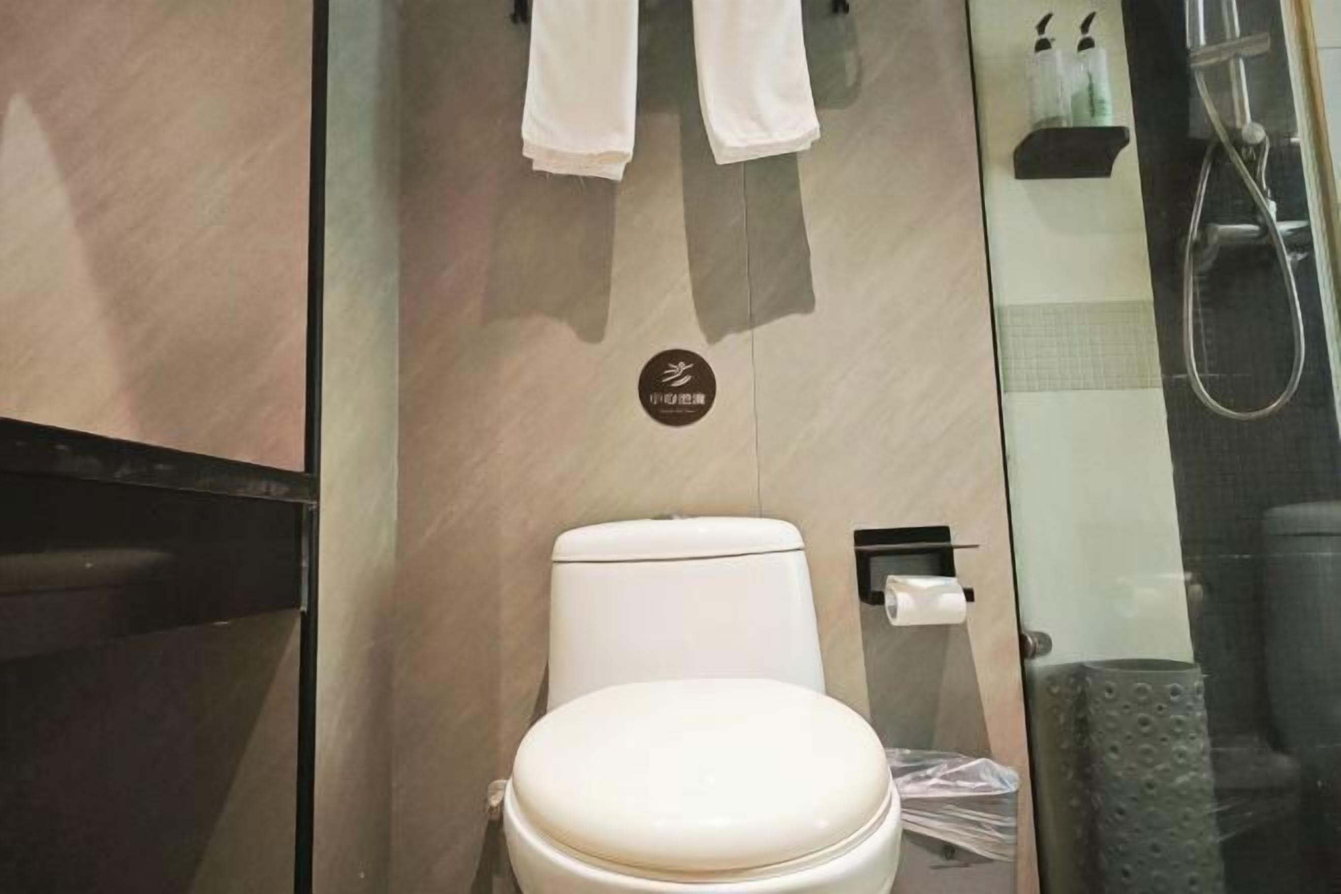 Ein modernes Badezimmer mit Toilette, einer Duschkabine aus Glas und einem Handtuchhalter.