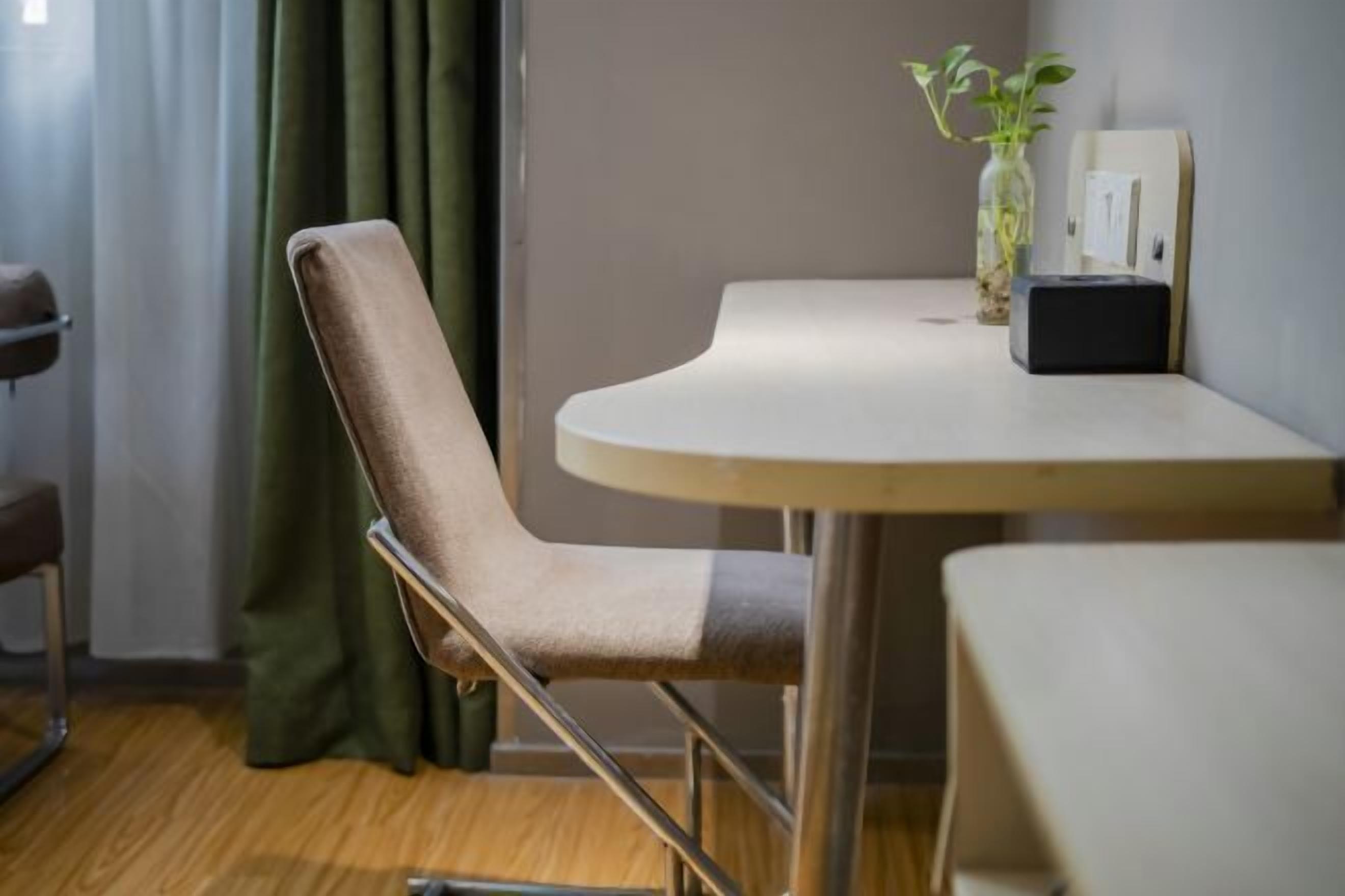Ein Zimmer mit einem runden Tisch, einem Stuhl, einer kleinen Pflanze und einer an der Wand befestigten Vorrichtung.