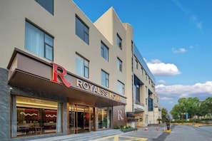 Un hotel amb un logotip prominent amb la lletra 'R', una façana moderna i un cel clar.