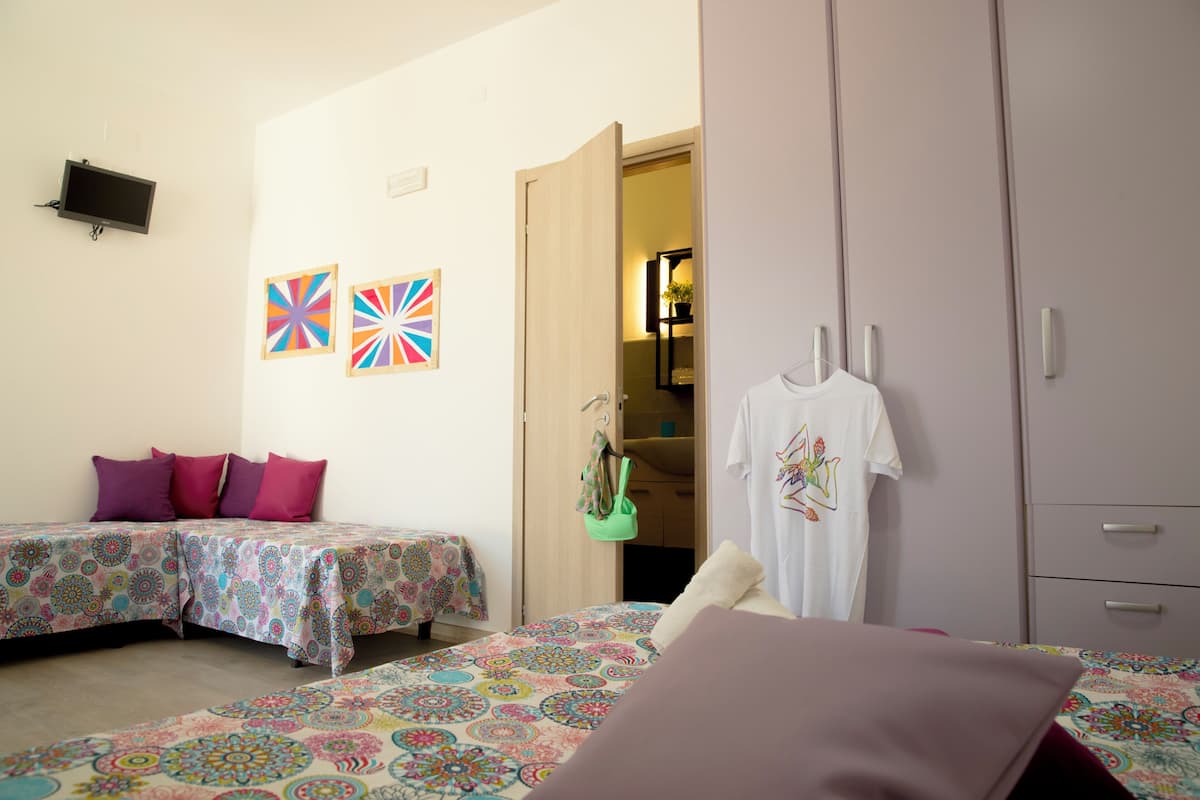 A bedroom with two beds, a wardrobe, and a television on the wall.