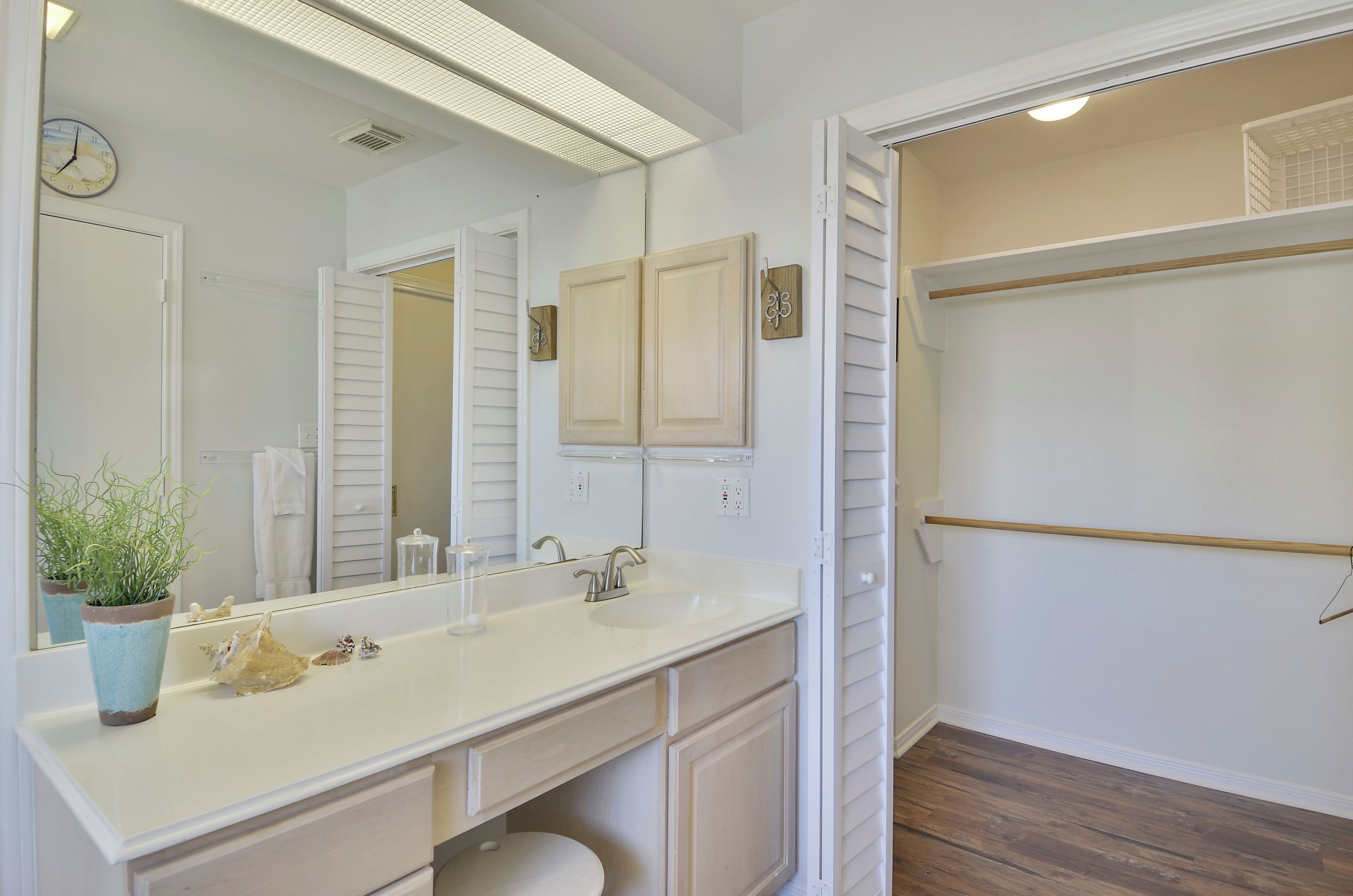 Une salle de bain avec un double vasque, un miroir, une plante en pot et un dressing.