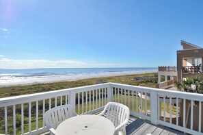 A deck with a table and chairs overlooking a beach. - Beachfront Dolphin by Ryson Vacation Rentals (Galveston)