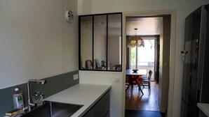 Una cocina moderna con un lavamanos, un espejo y una zona de comedor visible a través de una puerta abierta.