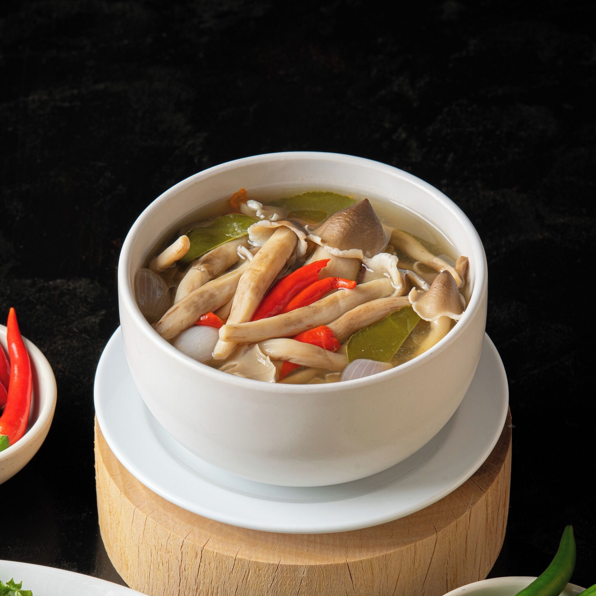 A bowl of soup with various ingredients on a wooden board.