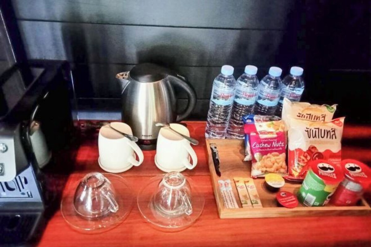 Et bord med elkedel, vandflasker, kaffekopper, juicer og snacks.