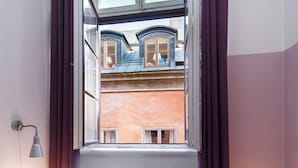 Ein Zimmer mit einem großen Fenster, einem Heizkörper und einem Bett mit Kissen.