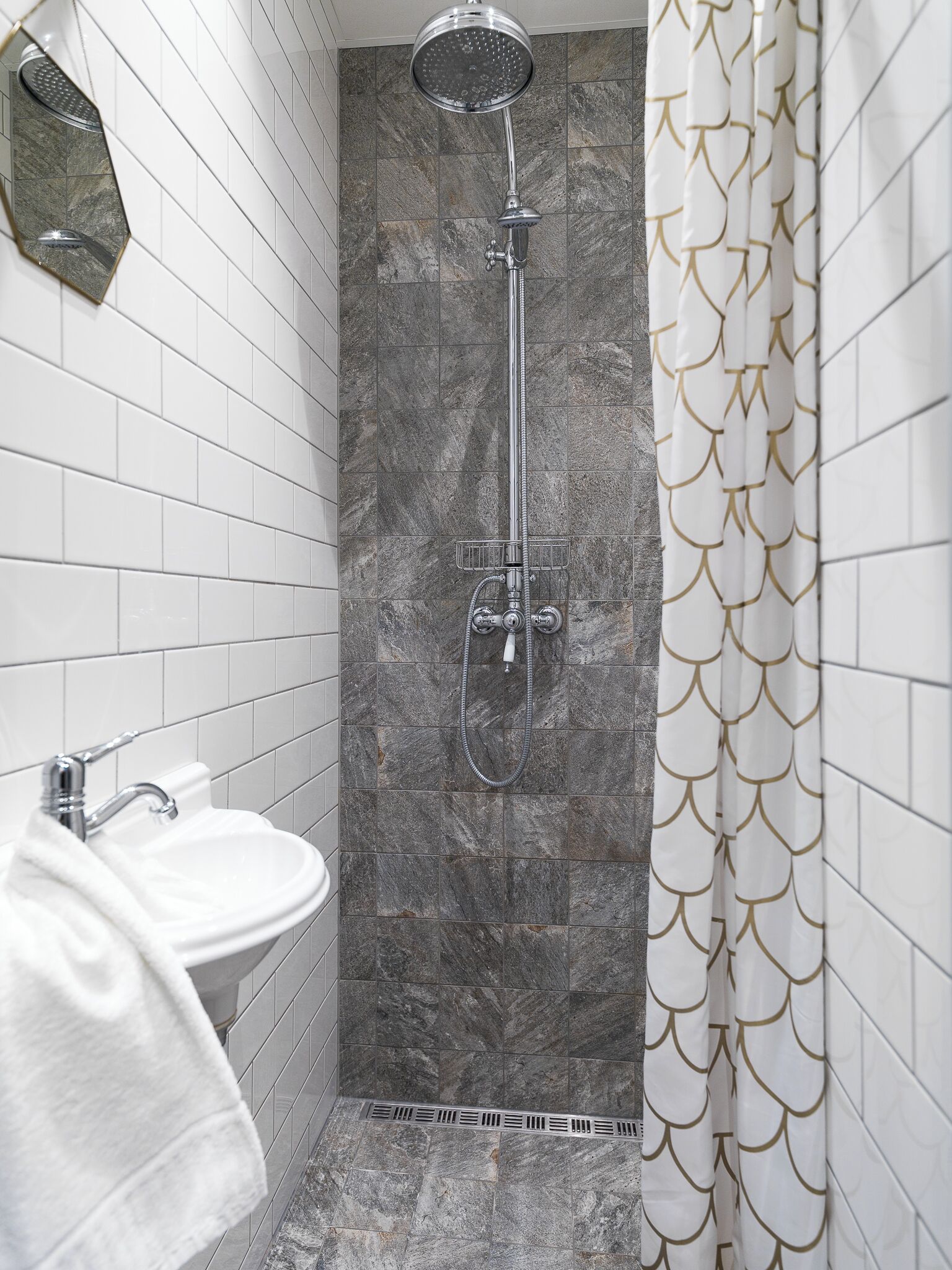 A bathroom with a shower, a sink, and a towel rack.