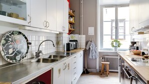 Eine moderne Küche mit weißen Schränken, Edelstahlgeräten und einem Fenster, das für natürliches Licht sorgt.