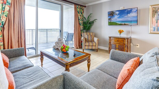 Een woonkamer met een bank, fauteuils, een salontafel en een televisie.