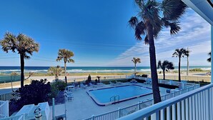 A pool area with lounge chairs, a pool, and a view of the beach and ocean. - Starboard Light 7 by Distinctive Beach Rentals (Ormond Beach)