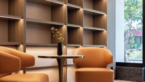 Een modern interieur met een houten boekenkast, een ronde tafel en twee oranje stoelen.