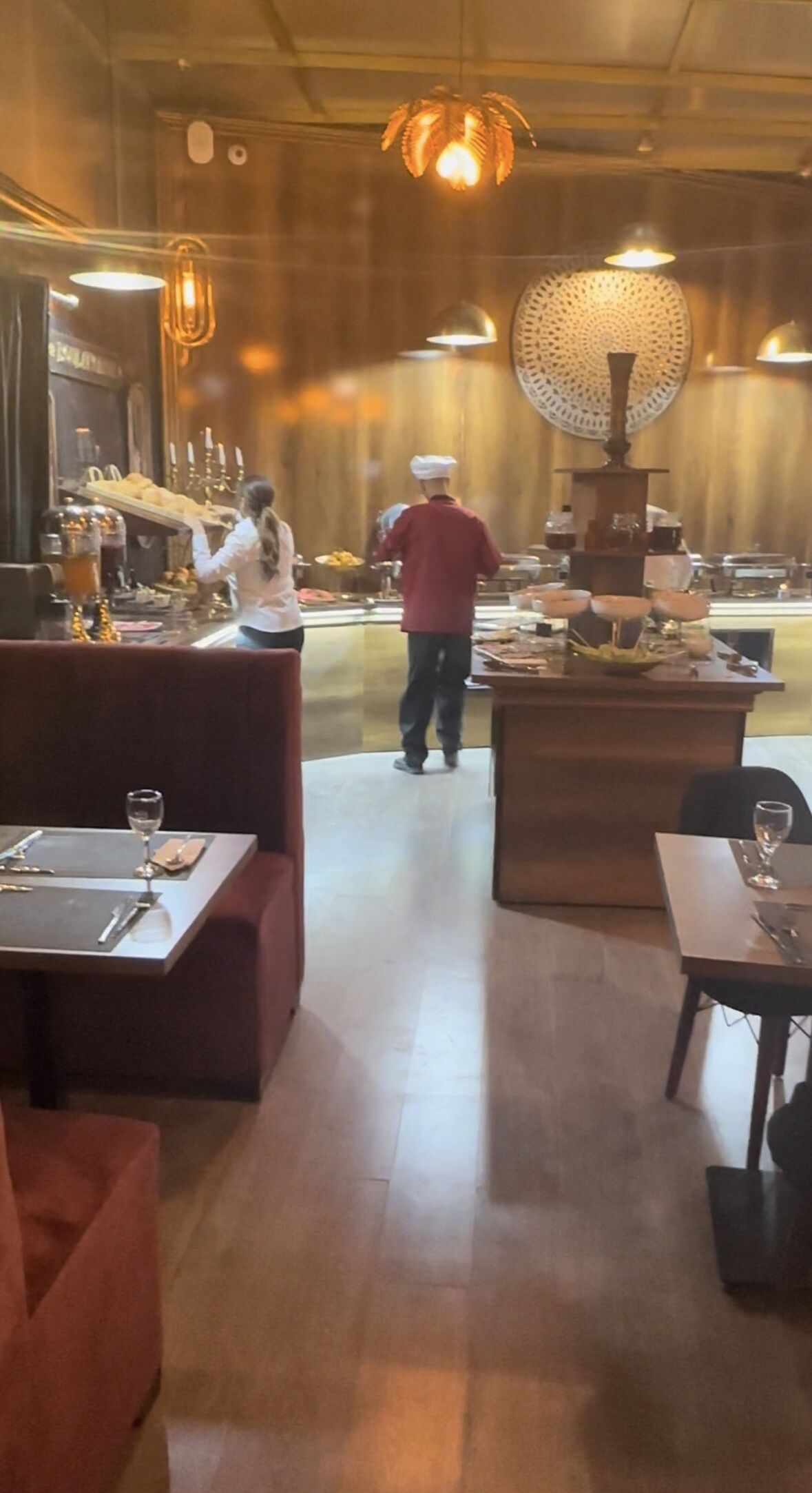 Interior de restaurante con decoración de madera, mesas dispuestas con copas de vino y una zona central de servicio.