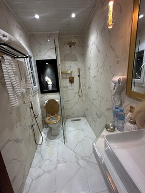 A modern bathroom with a marble floor, a toilet, a shower with a glass door, and a bathtub. - Hôtel LA BOURGEOISE (Marsa Ben M'Hidi)