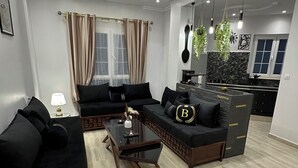 Ein modernes Wohnzimmer mit einer Sofagarnitur, einem Couchtisch und einer Küchenzeile im Hintergrund.