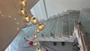 Ein modernes Interieur mit einer Marmortreppe, einer hängenden Leuchte und gerahmten Wandbildern.