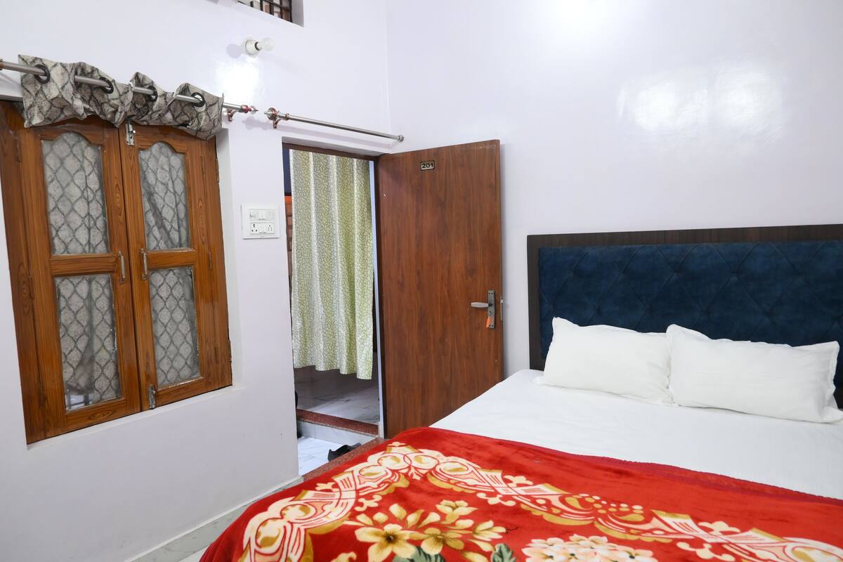Quarto com cama, guarda-roupa e janela com cortinas.