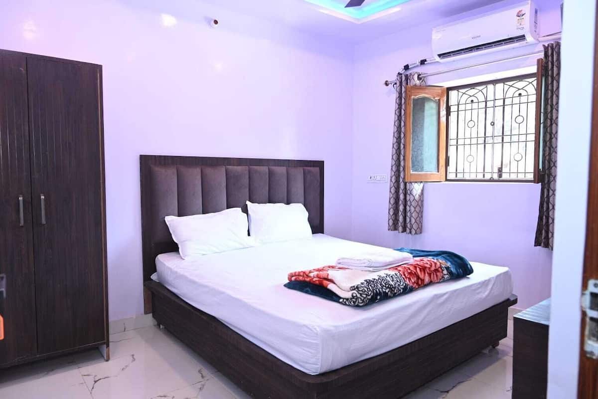 Quarto com uma cama grande, um guarda-roupa e uma janela com grades.