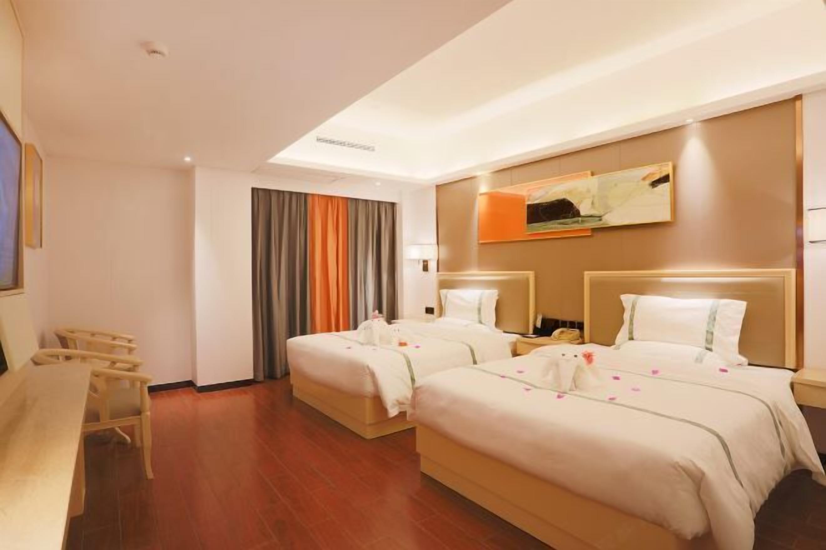 A hotel room with two beds, a dining table, and a painting on the wall.