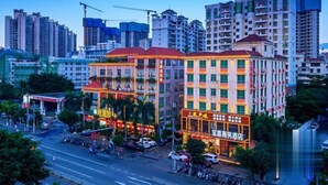 Un hôtel à plusieurs étages, avec une enseigne bien visible au centre, entouré d’immeubles de grande hauteur et bordé par une rue animée.