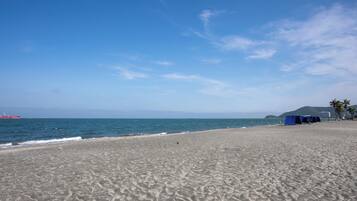 A beach with a sandy shore, a few tents, and a distant ship.