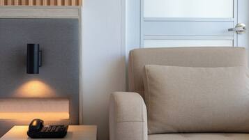 Una habitación moderna con sofá, mesita de noche con lámpara y aplique de pared.