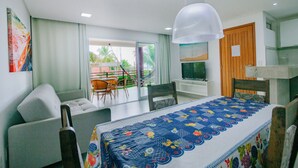 Habitación de hotel con cama, escritorio, silla, televisor y balcón con vistas a palmeras.