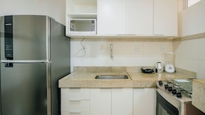 Cocina compacta con un refrigerador de acero inoxidable, un microondas, un fregadero y una estufa.