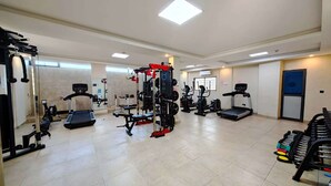 A spacious gym with various exercise equipment including treadmills, weight machines, and free weights. - Soluxe Hotel Cotonu (Cotonou)