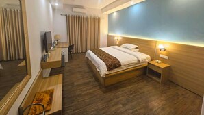 A modern hotel room with a large bed, a desk with a chair, a TV, and a mirror. - Soluxe Hotel Cotonu (Cotonou)