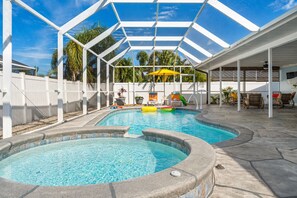 Una piscina con cerramiento de vidrio, rodeada de sillones de descanso y plantas en macetas.