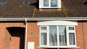 Une maison à deux étages, construite en briques, avec un toit en pente, une porte d’entrée et une plaque portant le numéro « 80 ».