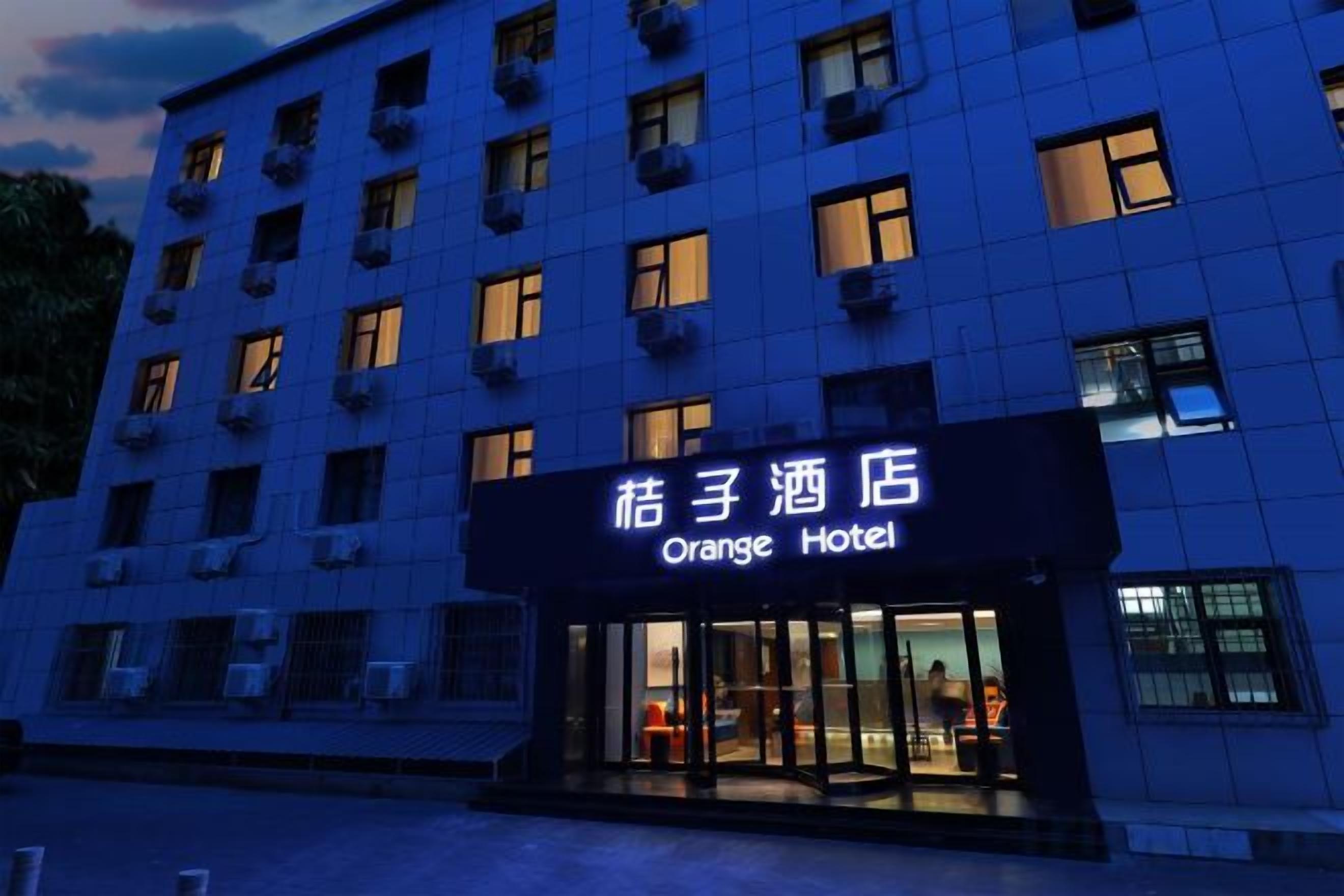 Un hotel con un cartel que dice 'Orange Hotel' y varias ventanas.