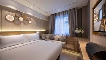 A modern hotel room with a large bed, a sofa, a TV, and a decorative wall panel.