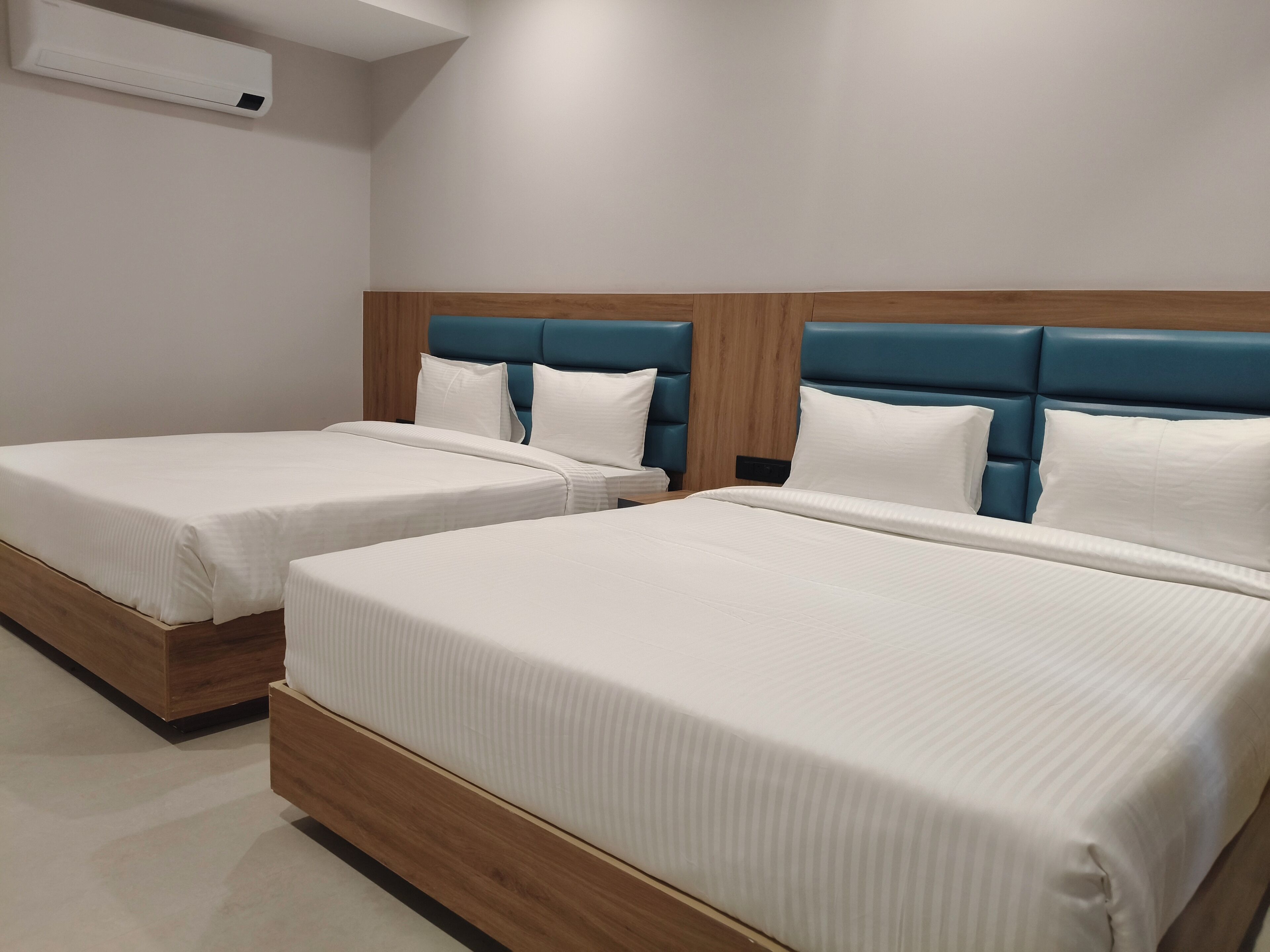 Two twin beds with wooden headboards and white bedding in a hotel room.