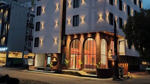 Un hotel a più piani dal design moderno, con un ingresso ben visibile caratterizzato da ampie finestre ad arco e una segnaletica che indica si tratta di un albergo.