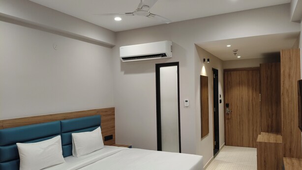Una camera d'albergo moderna con un letto grande, un comodino, una ventola a soffitto, un condizionatore d'aria e un armadio in legno.