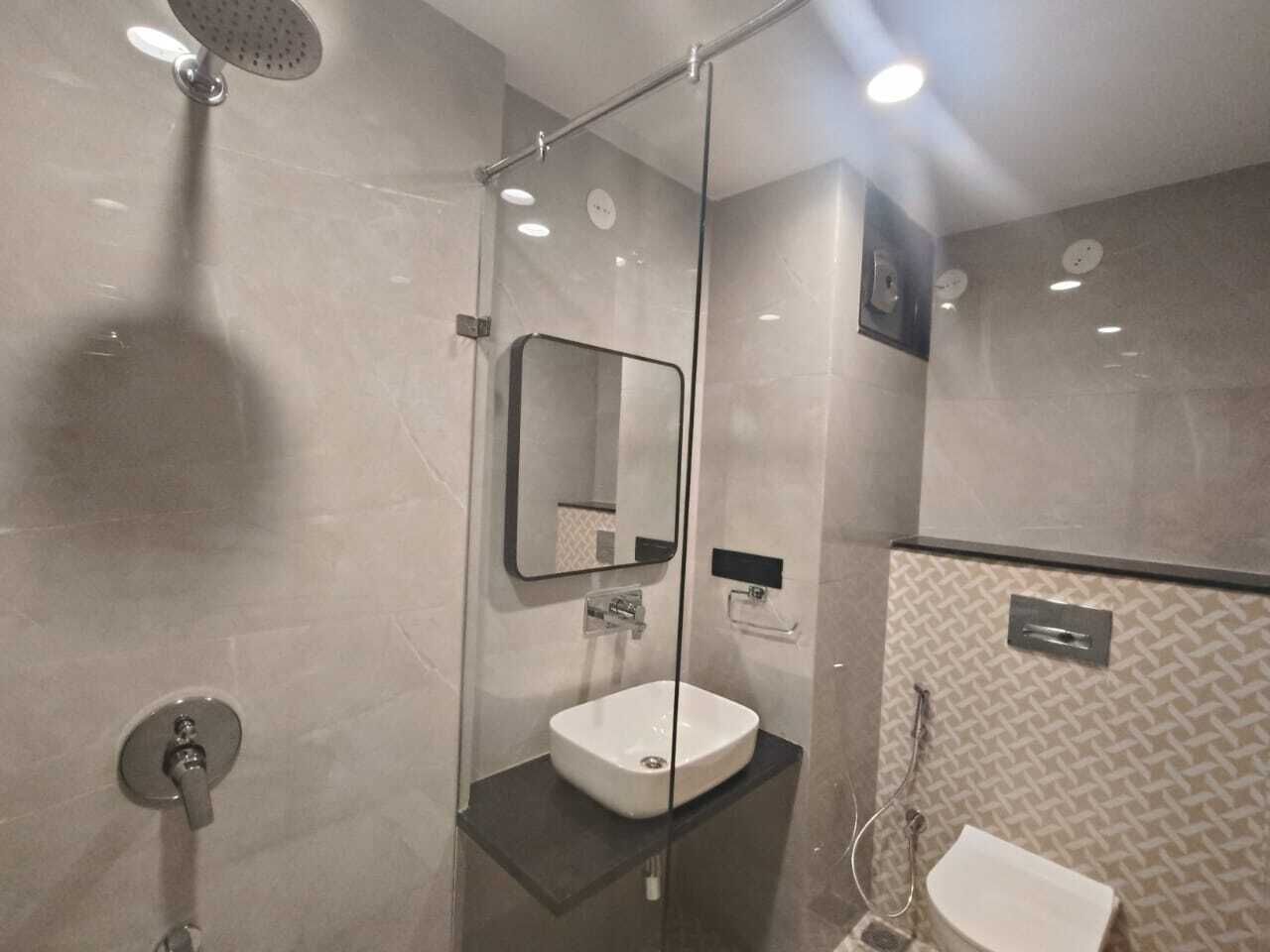 Un baño moderno con ducha de vidrio, lavamanos blanco y espejo.