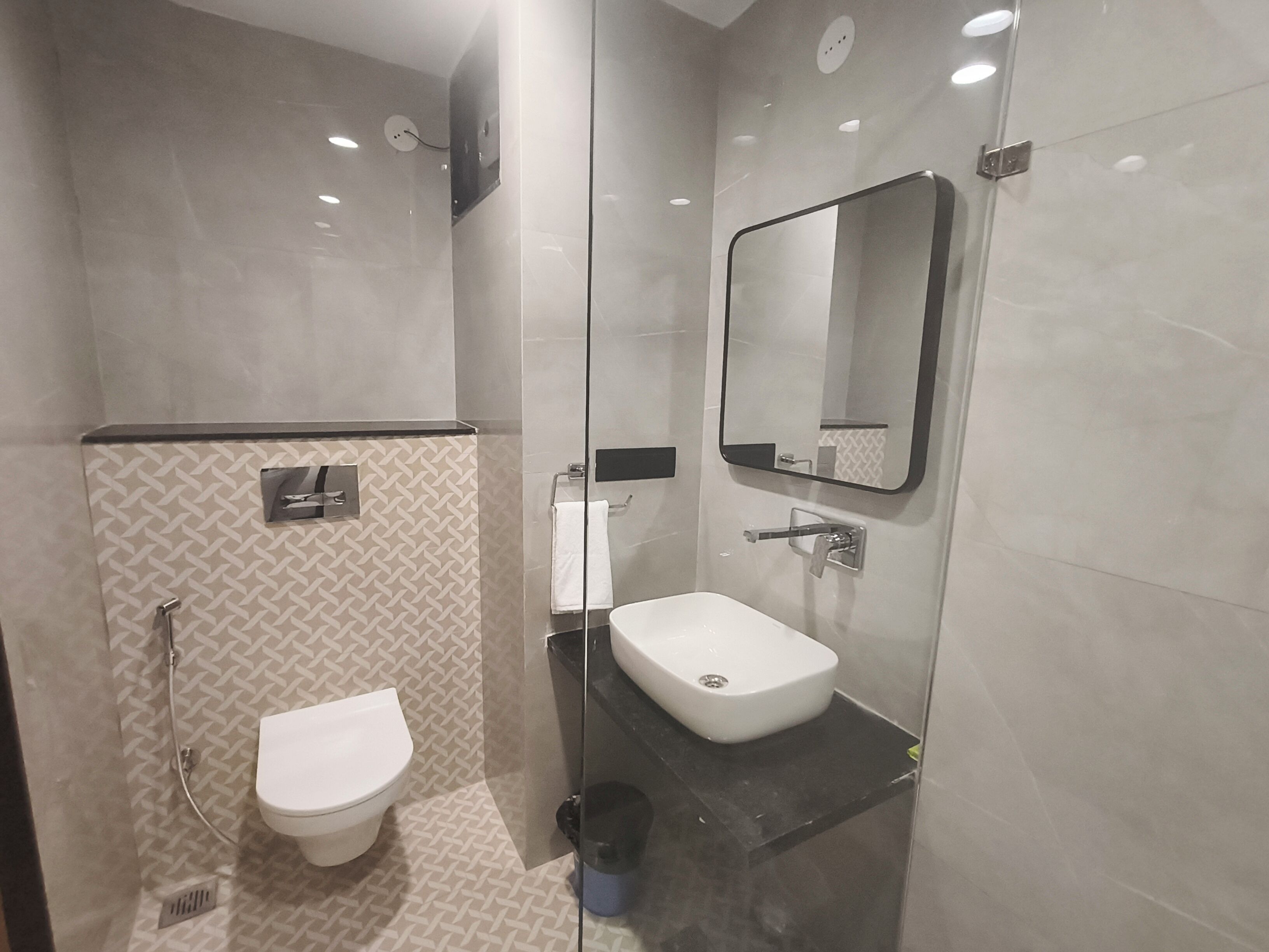 Un baño moderno con cabina de ducha de vidrio, inodoro y lavamanos con espejo.