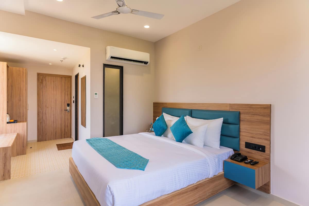 A modern hotel room with a large bed, a wooden headboard, a nightstand with a phone, and a ceiling fan.