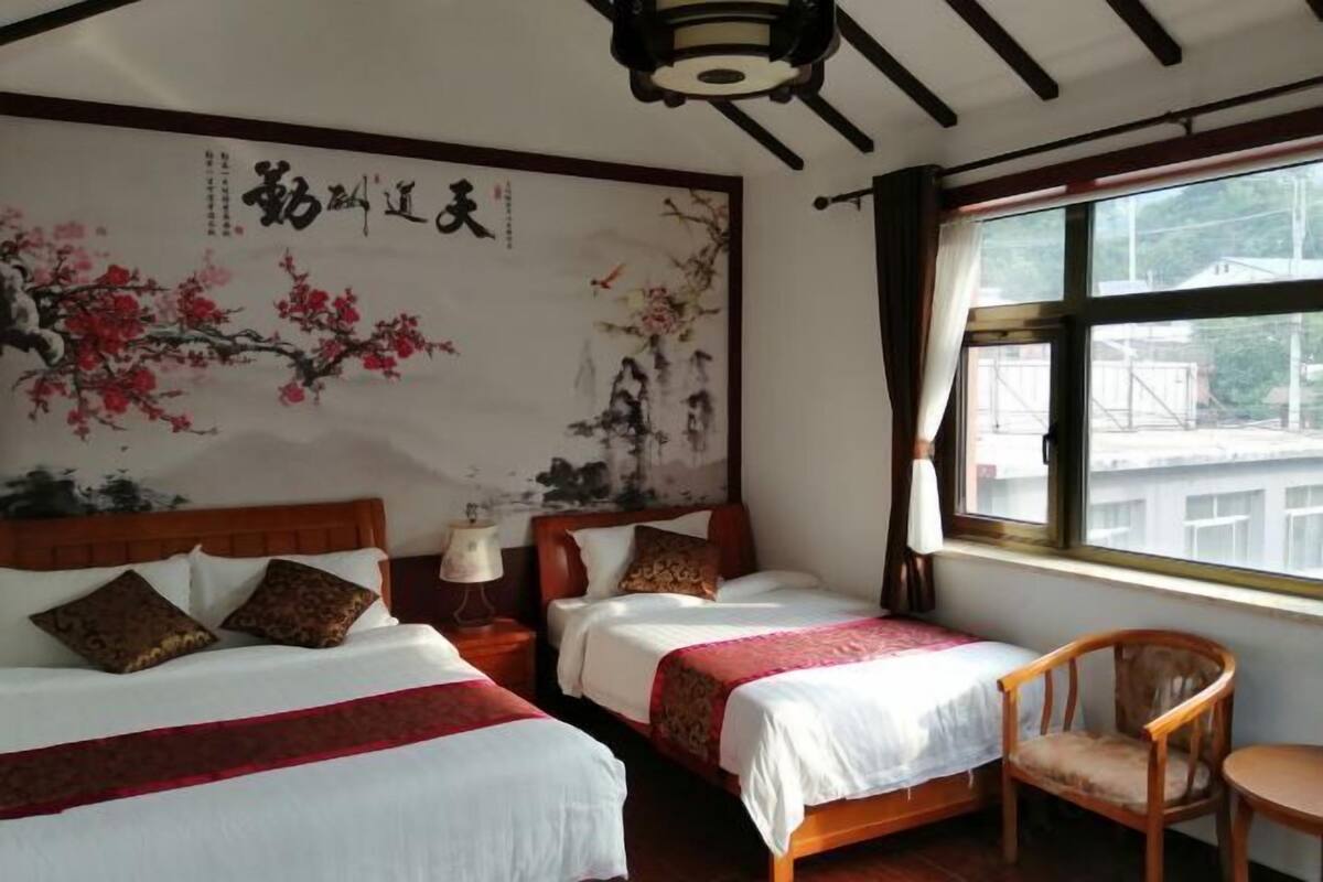 A hotel room with two beds, a wooden chair, and a large window.