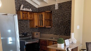 Eine Küche mit Holzausstattung, einem Edelstahlkühlschrank, einem eingebauten Ofen und einer gefliesten Rückwand.