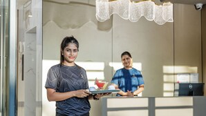 Et hotellets receptionsområde med moderne indretning, inklusive en reception og en lysekrone.